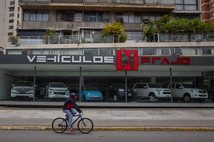 PANORAMA. Un ciclista pasa frente a un negocio de venta de carros usados el 29 de marzo de 2021 en Caracas (Venezuela). PANORAMA. Un ciclista pasa frente a un negocio de venta de carros usados el 29 de marzo de 2021 en Caracas (Venezuela).